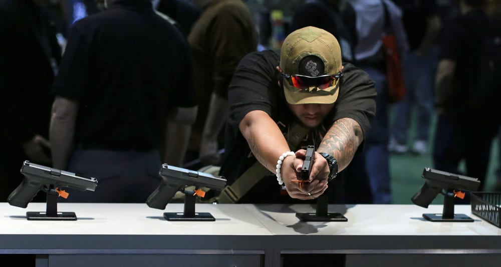 Firearms buyer Joshua Asperila checks out various Glock hand guns on display during the Shooting Hunting and Outdoor Trade Show, Tuesday, Jan. 14, 2014, in Las Vegas.