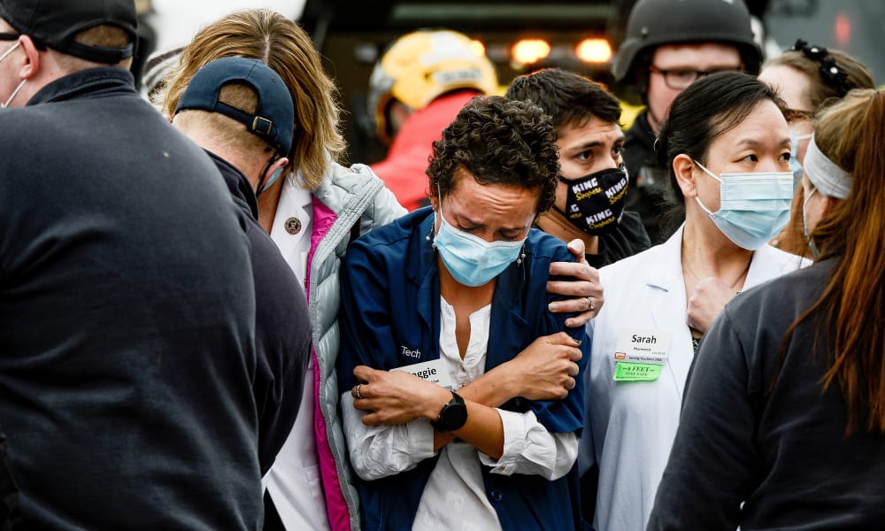 Image: A woman consoles a King Soopers pharmacy technician after a shooting at the grocery store in Boulder
