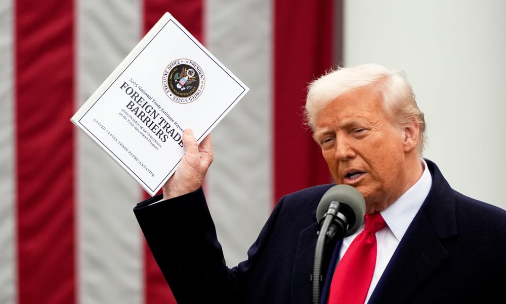 US President Donald Trump speaks during a tariff announcement, holding a "Foreign Trade Barriers" booklet.