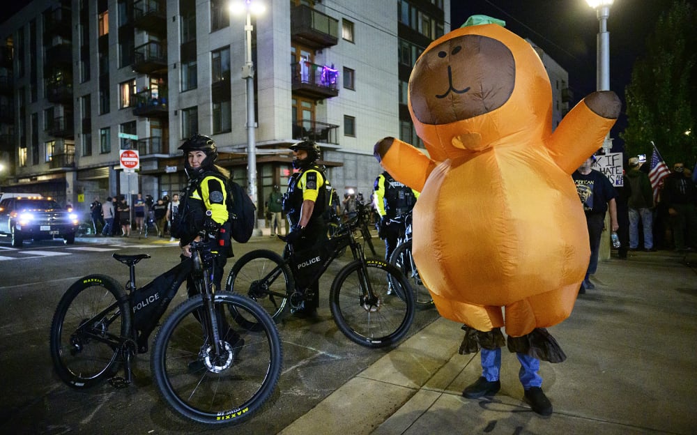 Portland Police officers stand watch as a protestors demonstrates near an Immigration and Customs Enforcement (ICE) facility.