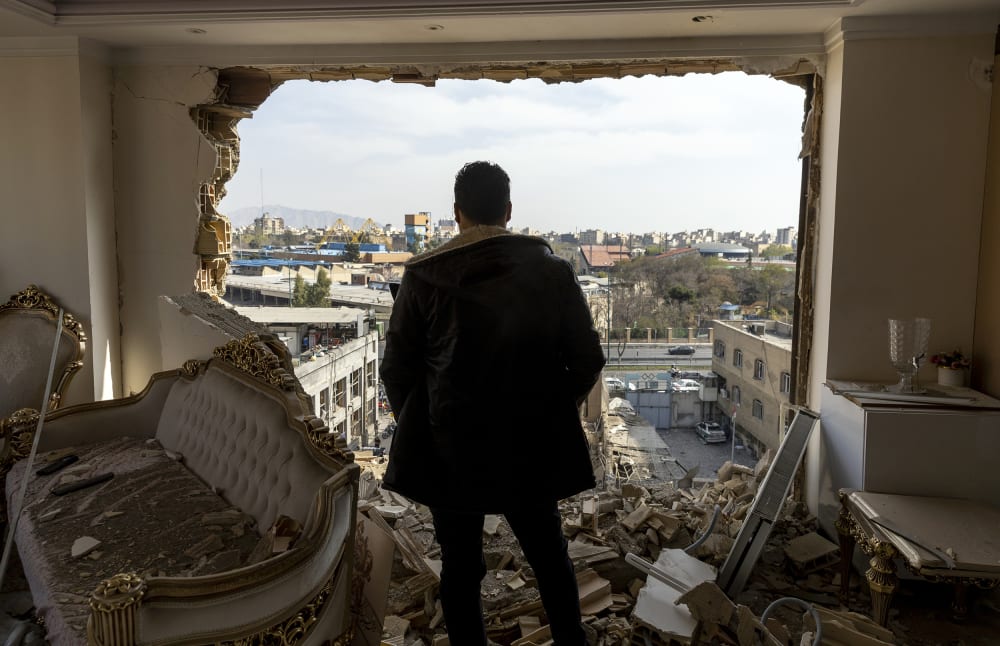 A man stands in a damaged residence after an airstrike.