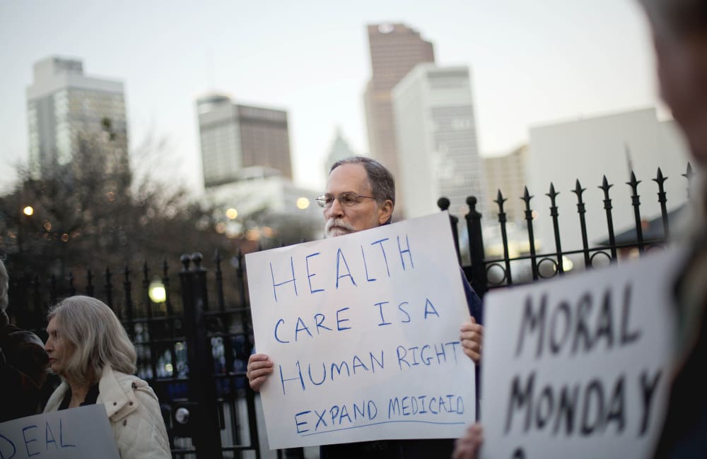 Bert Skellie, of Decatur, Ga., protests for Medicaid expansion outside the Wild Hog Supper, Sunday, Jan. 12, 2014, in Atlanta.