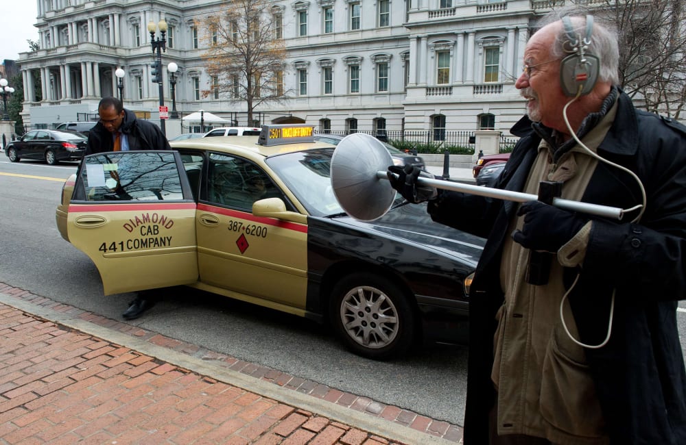 An activist dressed as spy using a listening device demonstrates at the Office of the U.S. Trade Representative in Washington, D.C., on December 16, 2013.