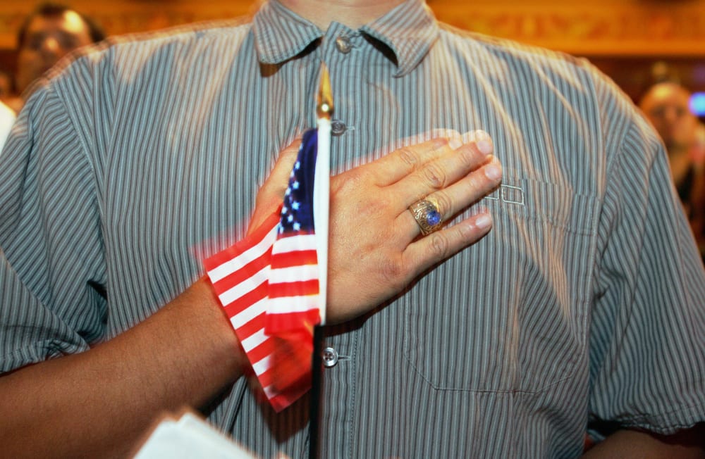 A person holds their hand up to their chest as they swear allegiance to the U.S. flag during a naturalization ceremony in Miami, F.L., on April 28, 2006.