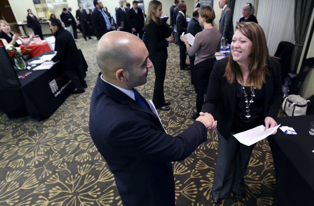In this Monday, Feb. 25, 2013, photo, Sayed Mouawad, left, of Providence, R.I., shakes hands with Jillian Wallace of Matix, Inc., during a job fair in Boston. The number of people seeking U.S. unemployment aid fell to a seasonally adjusted 340,000 in...