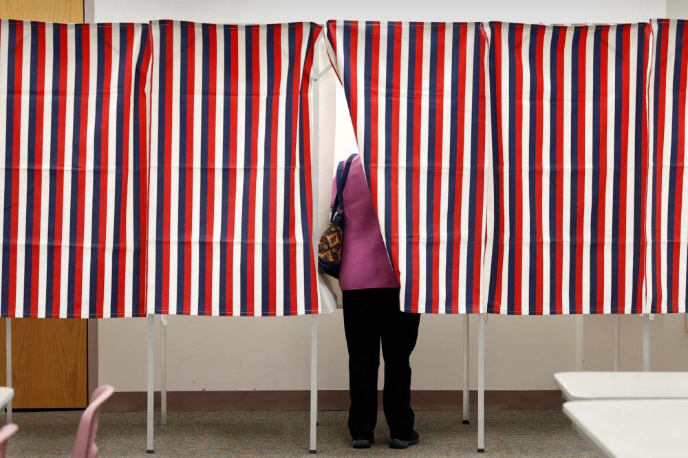 Image: A voter stands in voting booth while voting in the New Hampshire U.S. presidential primary election in Manchester