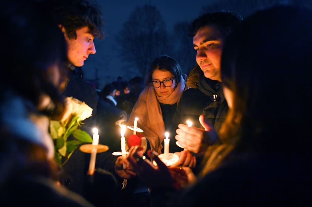 People hold candles during a vigil for those injured and killed during the Saturday shooting at Brown University.