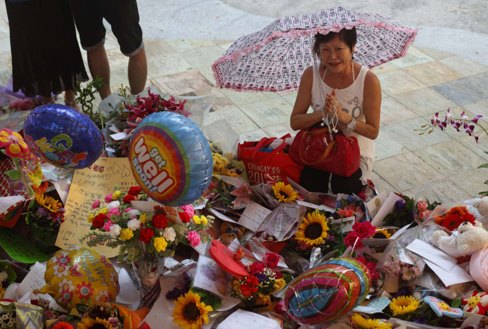 A woman weeps as she prays in the rain at a well-wishing corner for Singapore's former Prime Minister Lee Kuan Yew at the Singapore General Hospital March 22, 2015. (Photo by Edgar Su/Reuters)