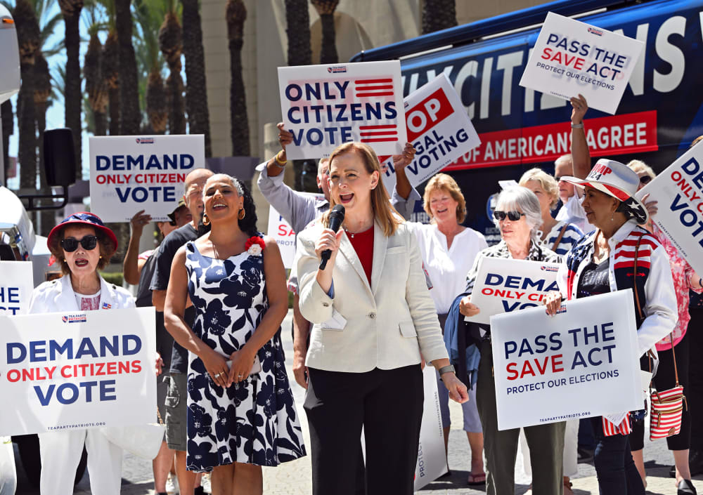 People hold signs saying "Only Citizens Vote" and "Pass the SAVE Act" outside.