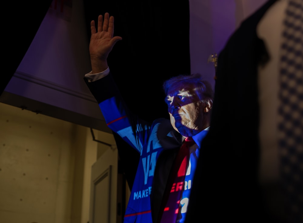 Donald Trump in Charlotte, N.C., with a projection of a Trump 2024 poster casting onto him.