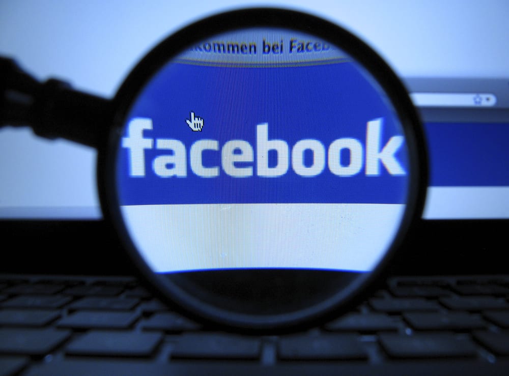 A magnifying glass is posed over a monitor displaying a Facebook page in Munich on Oct. 10, 2011. (Photo by Joerg Koch/AP)