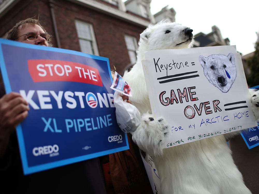 Demonstrators hold signs as they protest near the site of a fundraiser on April 3, 2013 in San Francisco, California. Hundreds of protesters staged a demonstration against war and the Keystone XL pipeline outside of a fundraiser to be attended by U.S....