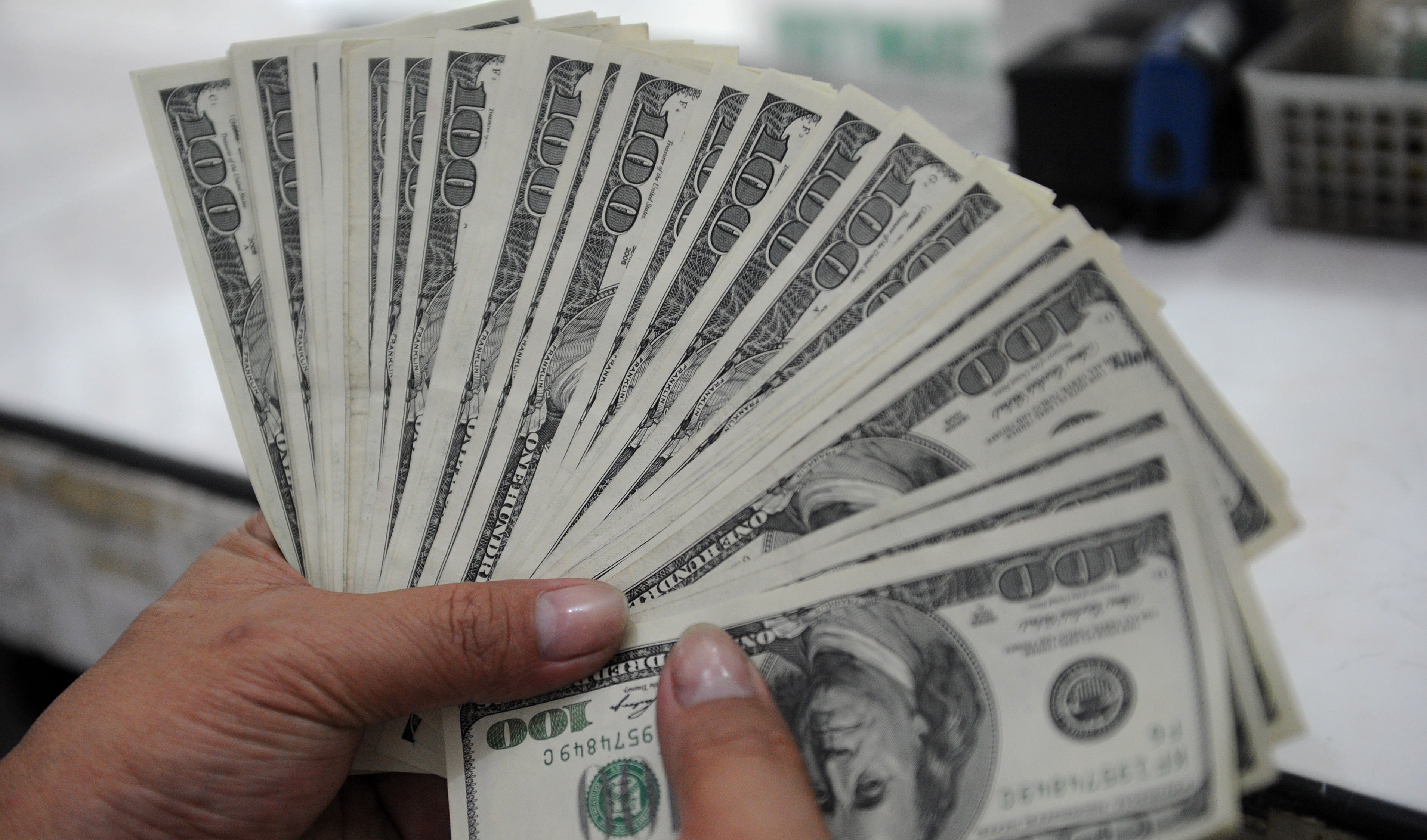 An employee at a money changer counts $100 bills.