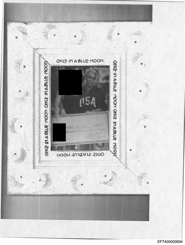 An undated photo of Jeffrey Epstein with an unnamed person redacted by the Department of Justice holding a check.