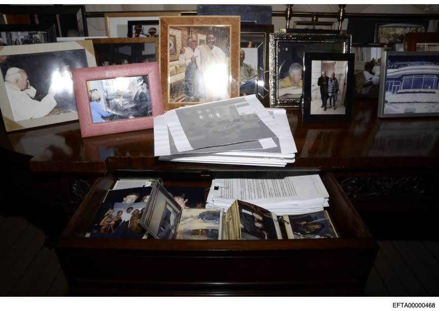 Framed photos and photo albums with people including Bill Clinton, Donald Trump and Ghislaine Maxwell.