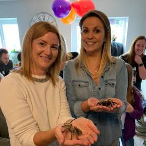 Two ladies handling tarantulas at a birthday party in their house