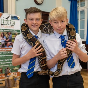 Two school boys handling a large snake.