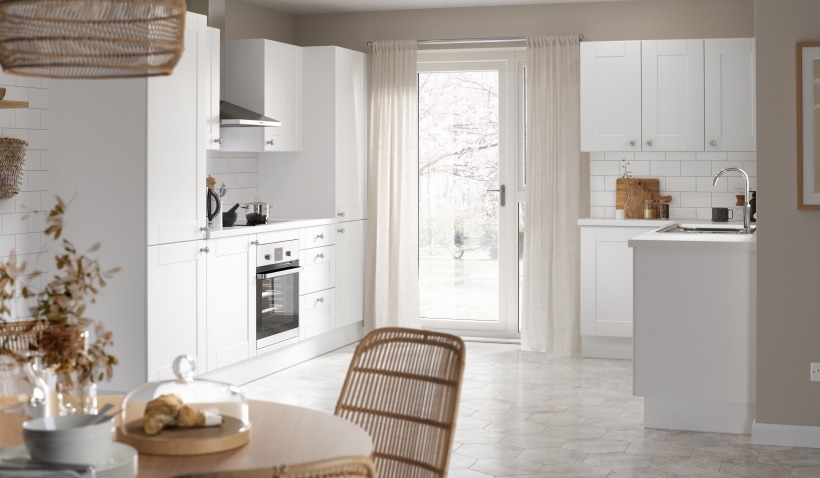 Hero shot of the Shaker Classic Kitchen in White Matt featuring integrated appliances and round dining table