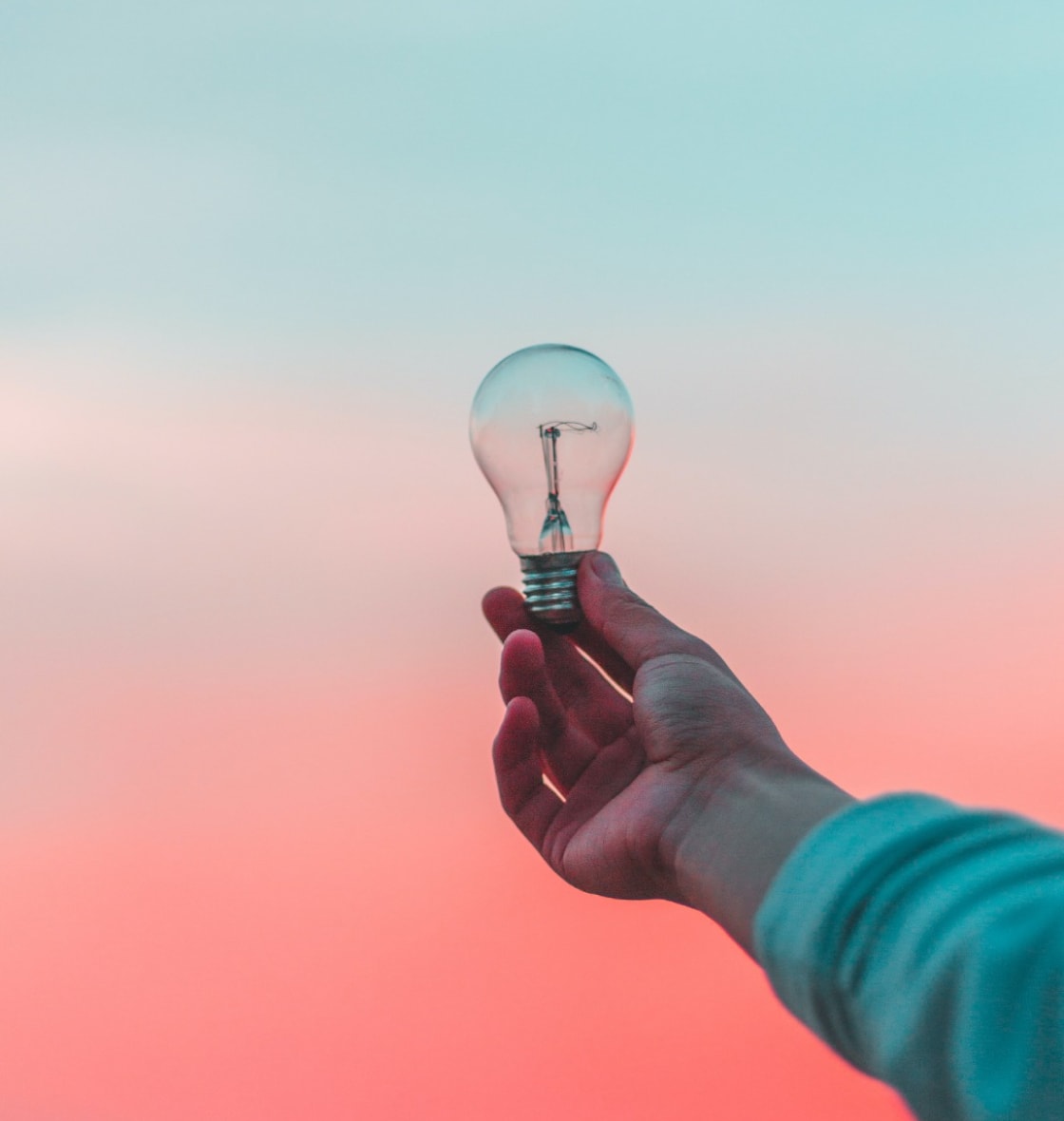 Hand holding a lightbulb outdoors