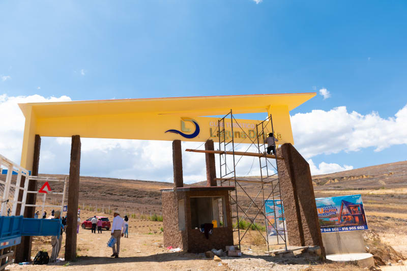 El pórtico de ingreso amarillo con el letrero del Club Turístico Laguna Dorada, con un operario montándolo sobre andamios