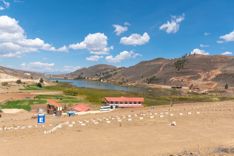 El terreno lotizado con sus hitos de concreto en primer plano, la Laguna San Nicolás al fondo y los cerros detrás, en un día despejado