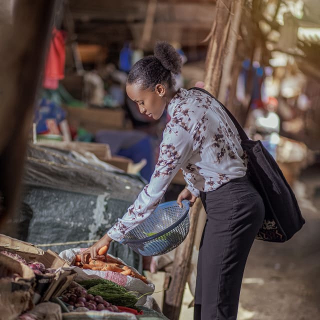 A young woman selecting vegetables at an outdoor market