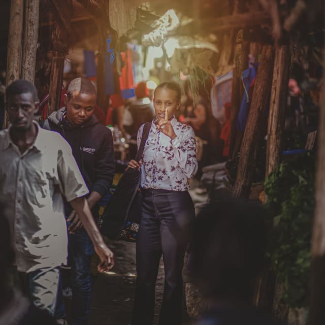 A film crew following a woman through an outdoor market