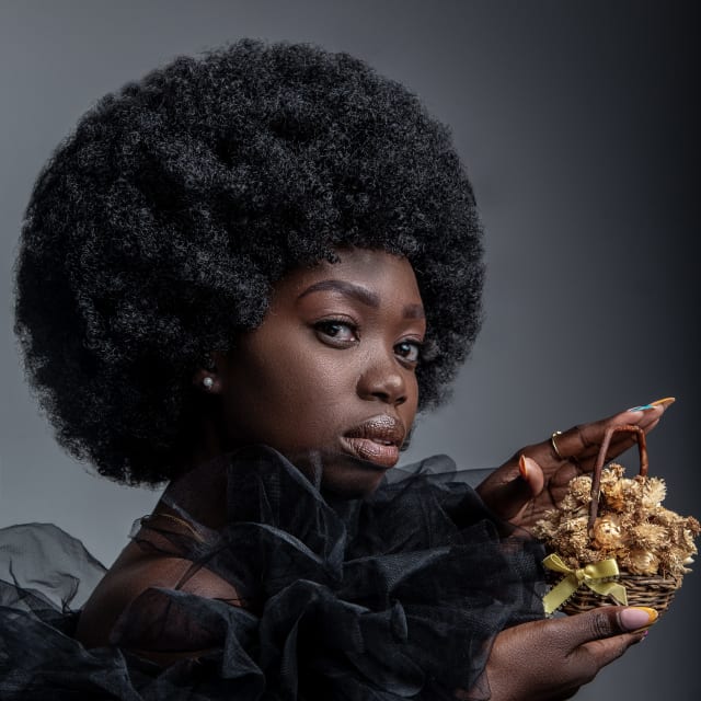 Studio portrait of a woman with an afro holding dried flowers