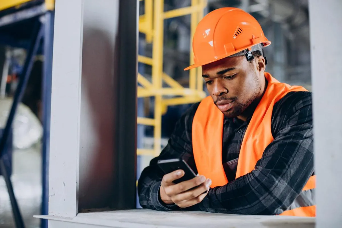 A worker in a hard hat answering screening questions on his phone