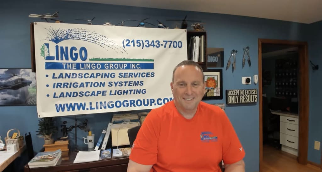 Gavin Lingo in the office, sitting in front of a company sign. Gavin Lingo in the office, sitting in front of a company sign.