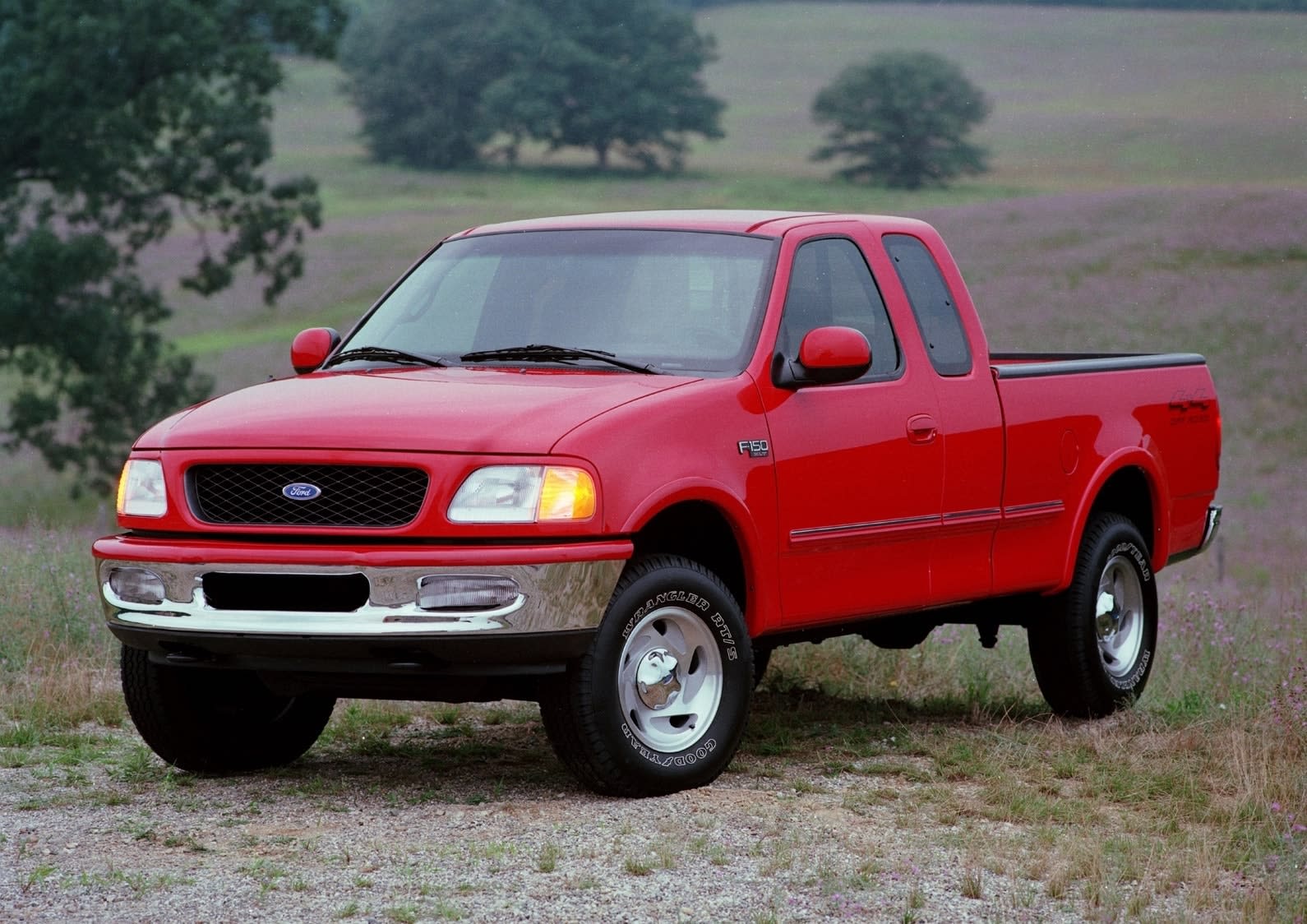 Generation 10 (1997–2003) Ford F-150 SuperCab in red colour in a field with trees in the background.