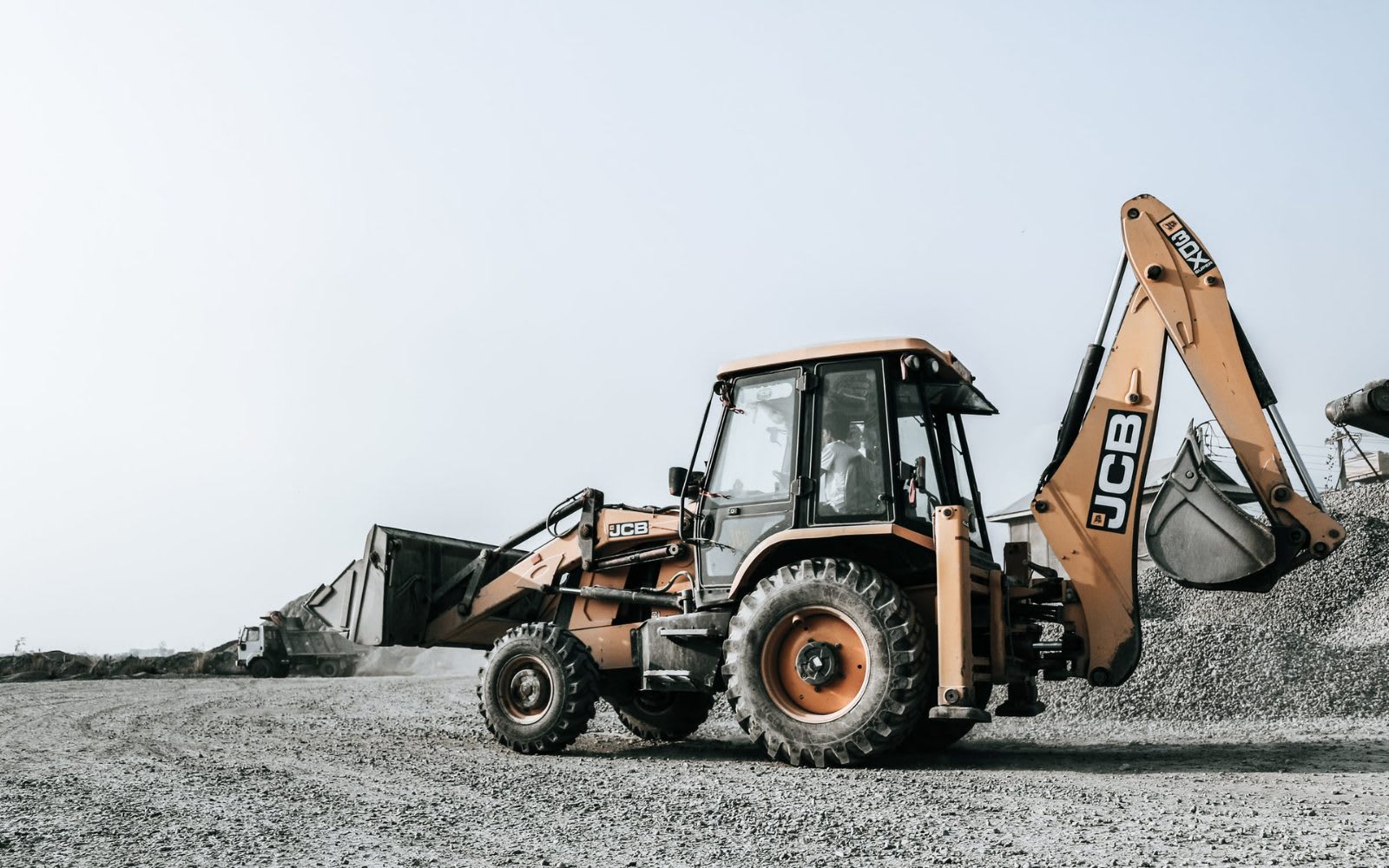 Backhoe loader driving at a construction site.