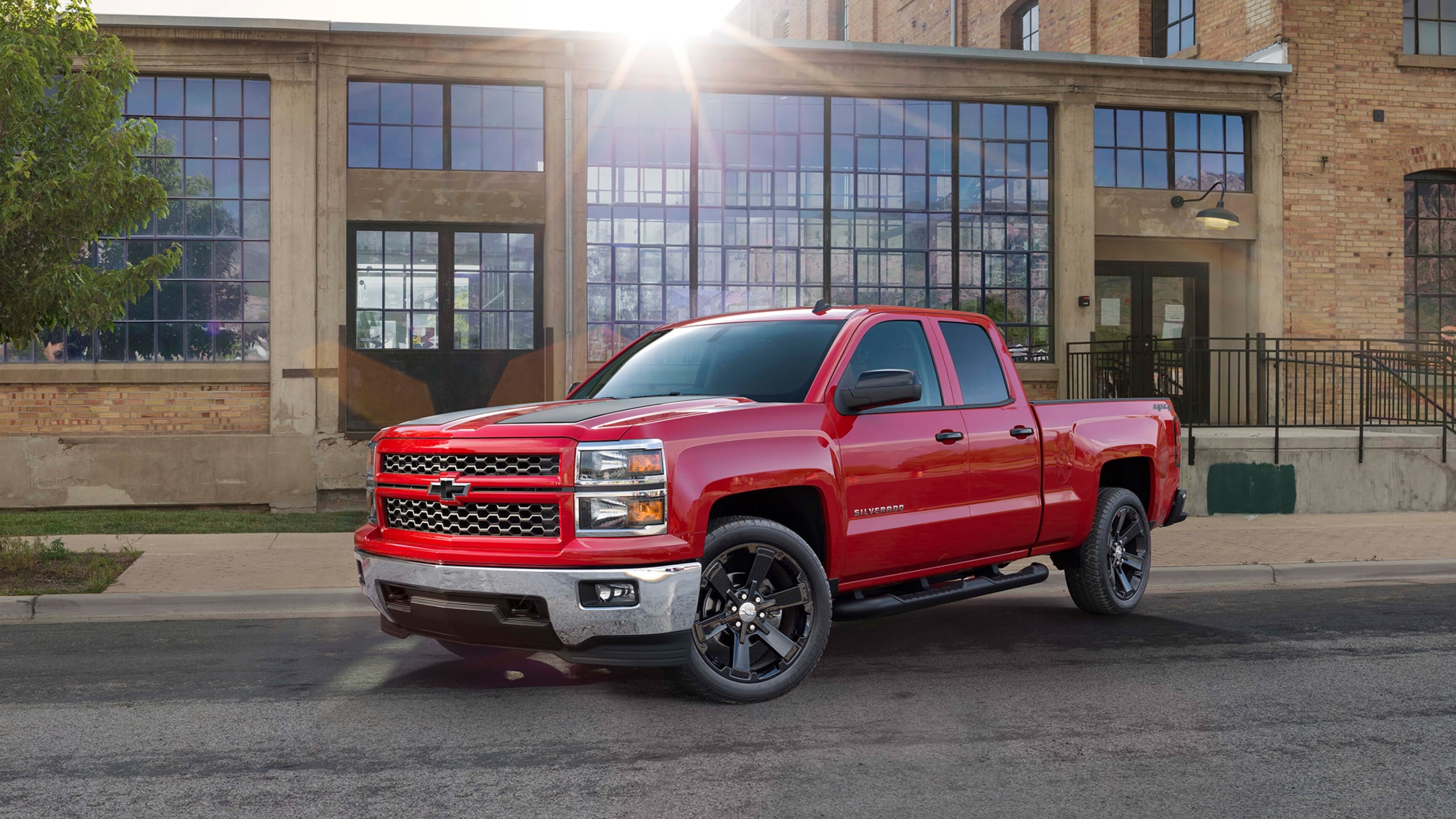 Red Chevy Silverado diesel vehicle with large towing capacity, parked in front of a building on a sunny day.