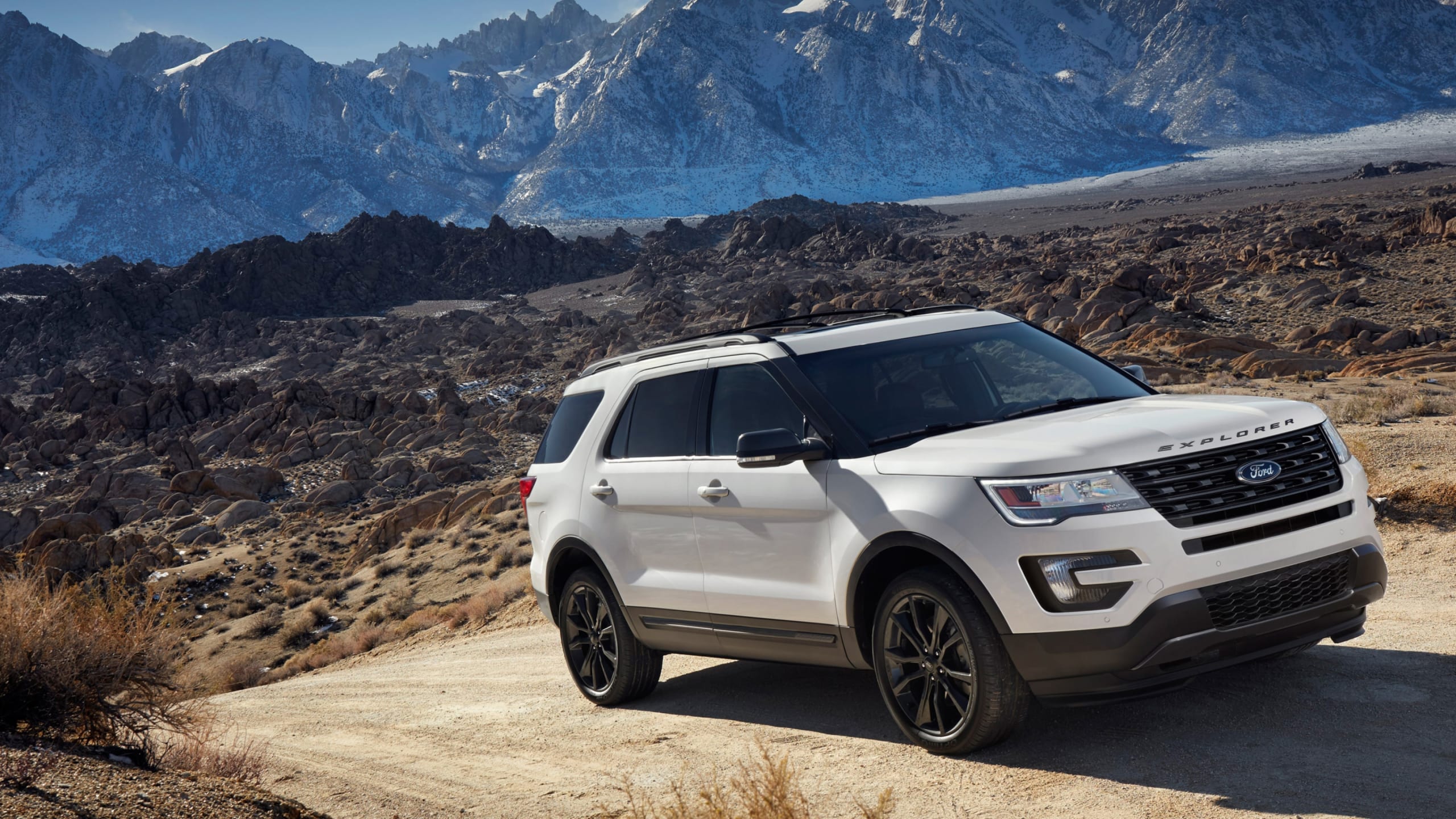 White Ford Explorer driving in the mountains, offering a significant amount of space for cargo.