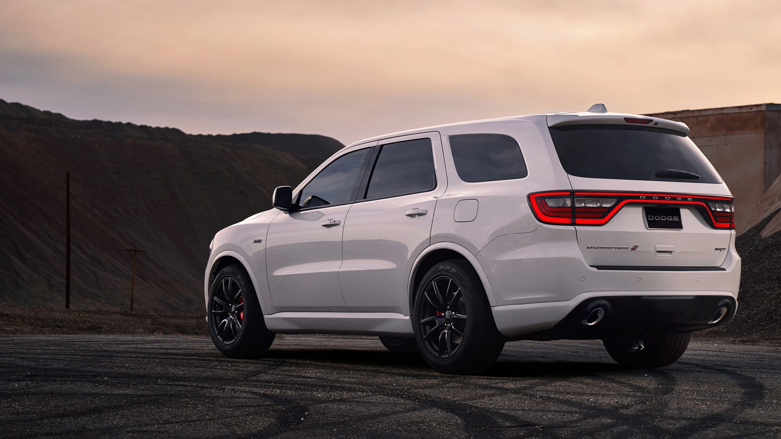 White Dodge Durango parked among black hills.