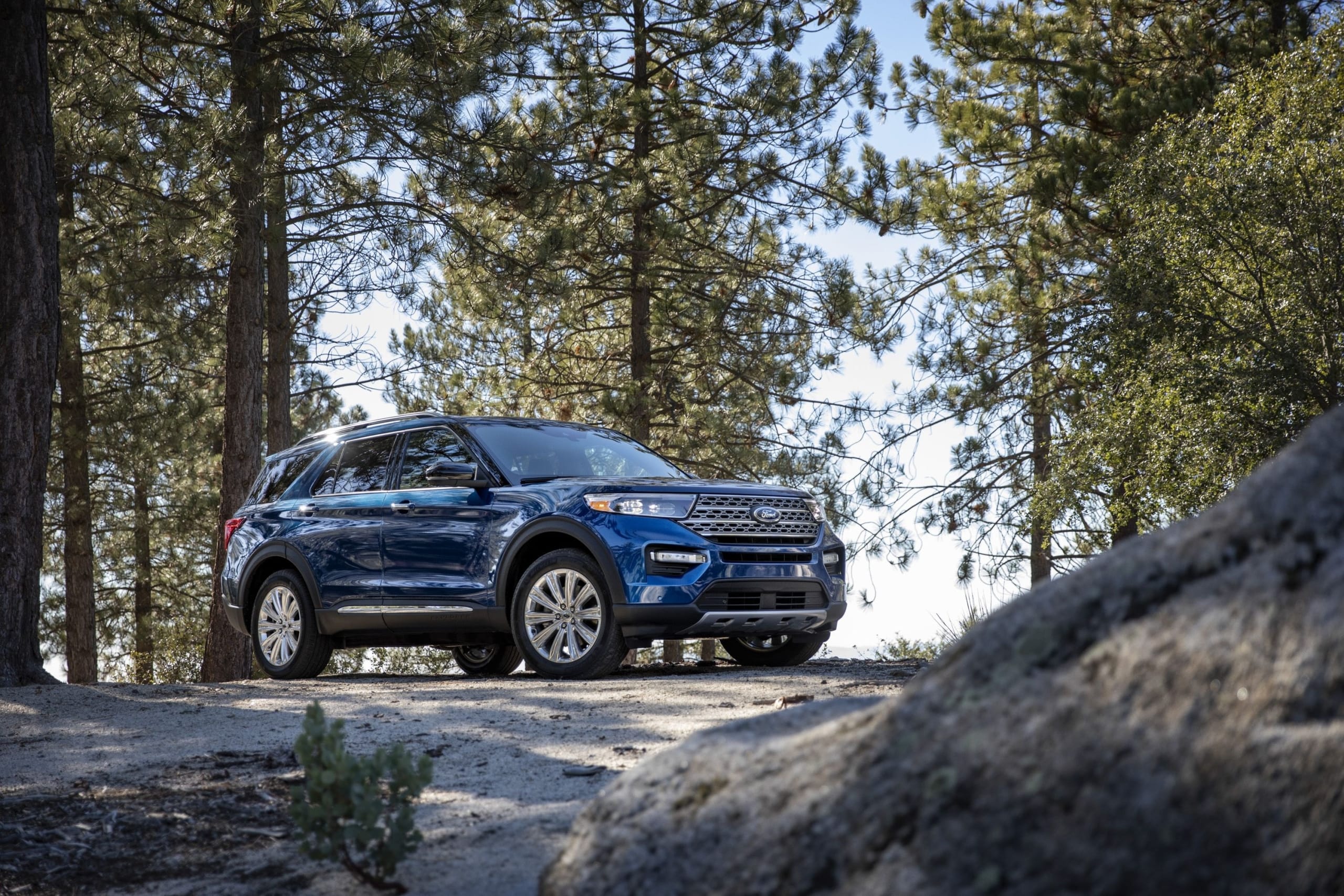 Dark blue Ford Explorer sport utility vehicle parked in the forest offering second row and third row seating.