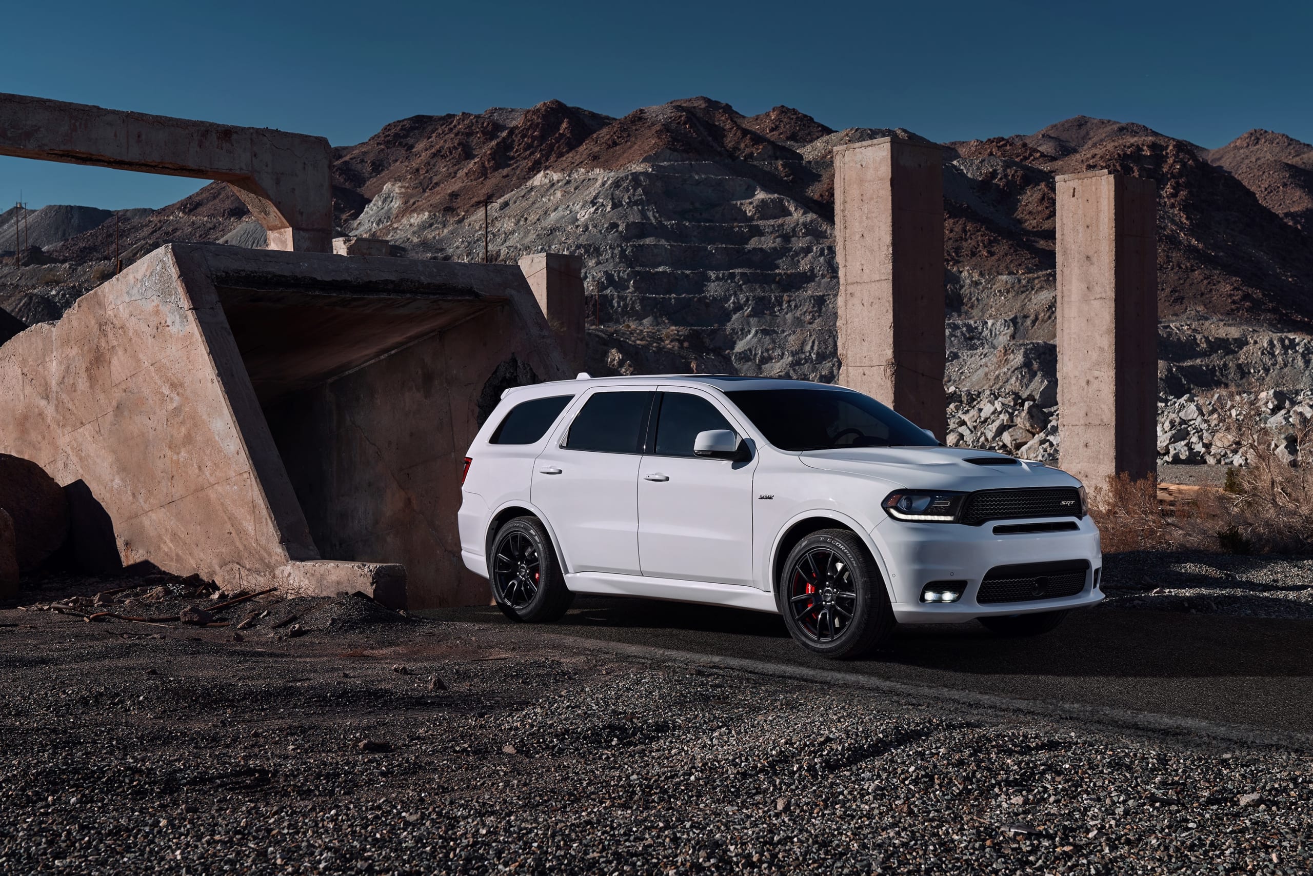 White Dodge Durango parked at a work site, with big machinery in the background and piles of gravel.