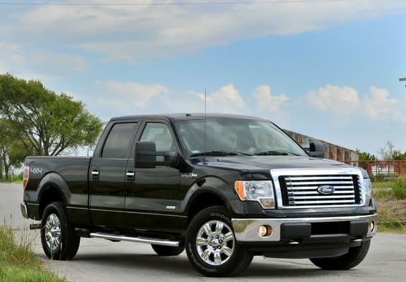 Black 2010 model year Ford F-150 truck on a road at the farm.