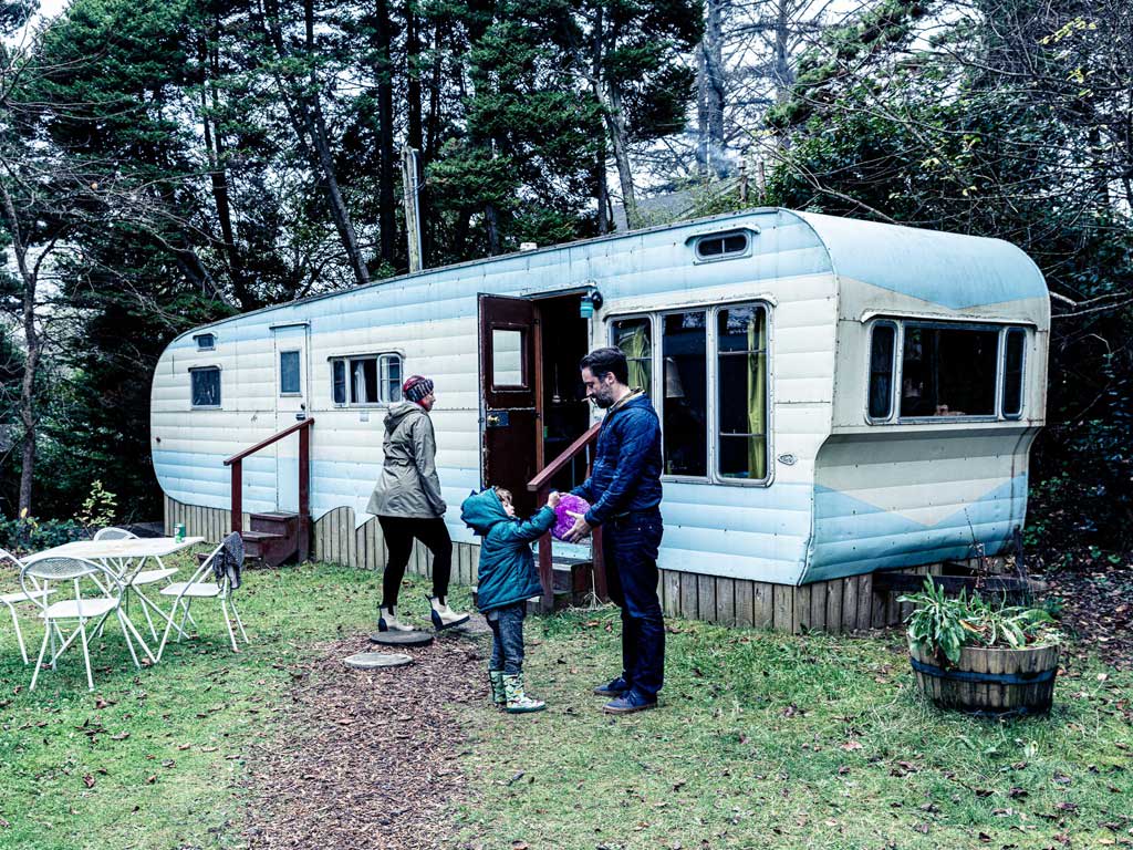 Cozy trailer at Sou'wester Lodge with family members enjoying outdoor bonding, surrounded by greenery and picnic seating.