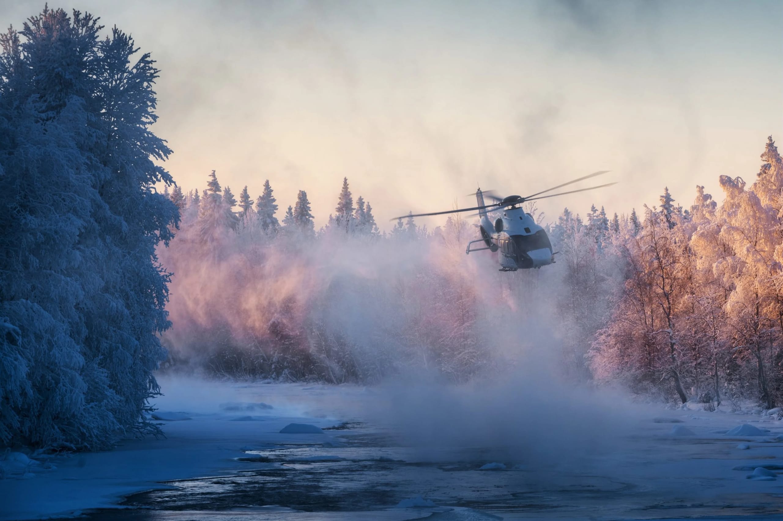 Helicopter flying over a snowy landscape with frosted trees and mist, representing Hillsboro Aviation's aviation services.