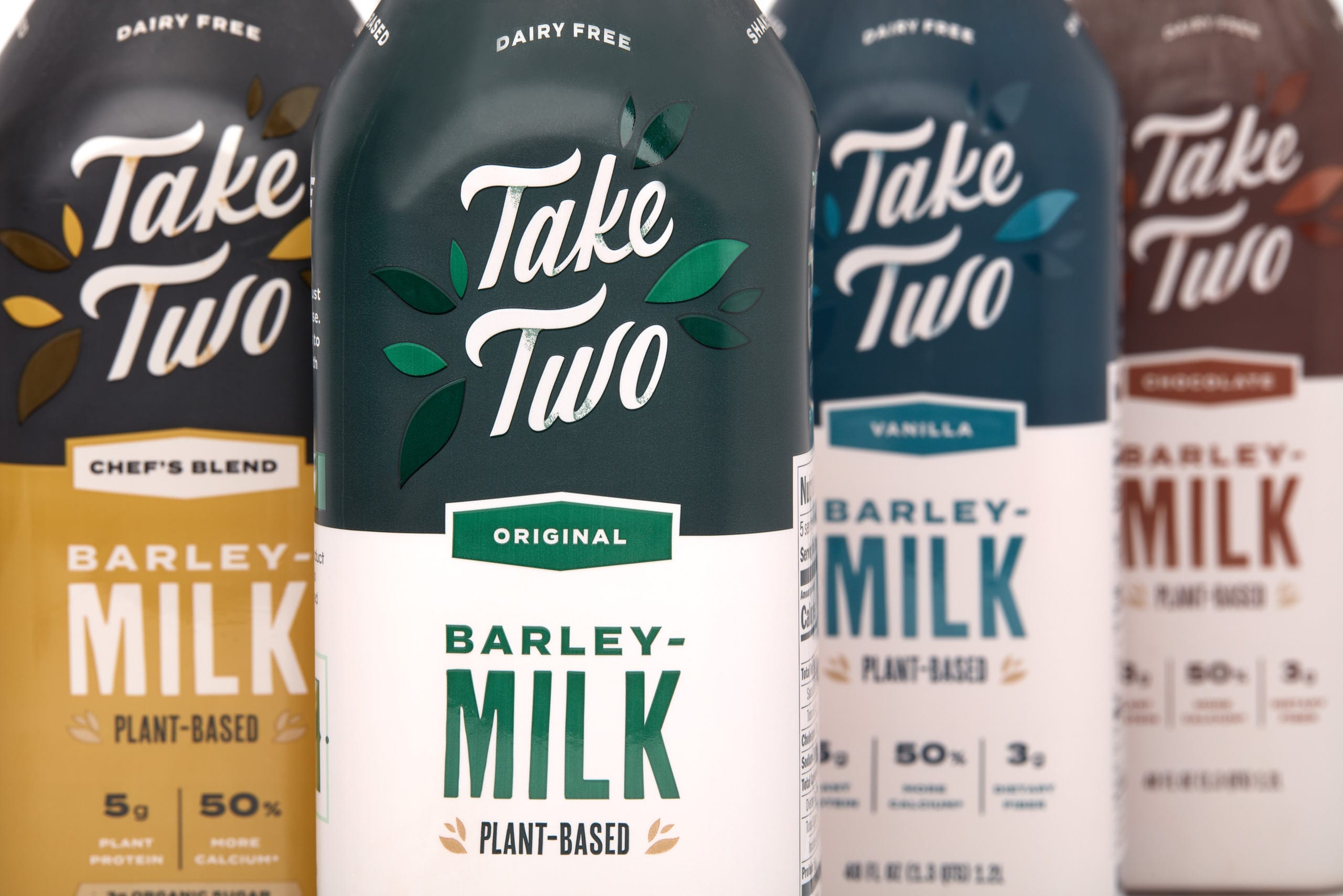 Take Two Foods plant-based barley milk bottles featuring Original, Vanilla, and Chef's Blend varieties, emphasizing dairy-free and sustainable branding.