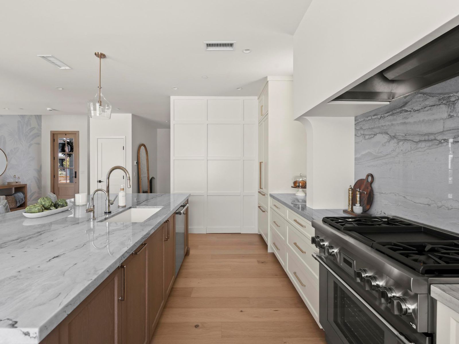 Kitchen by Murray Lampert with a hidden pantry behind flush white cabinet panels, quartzite-look countertops, and a professional-style range