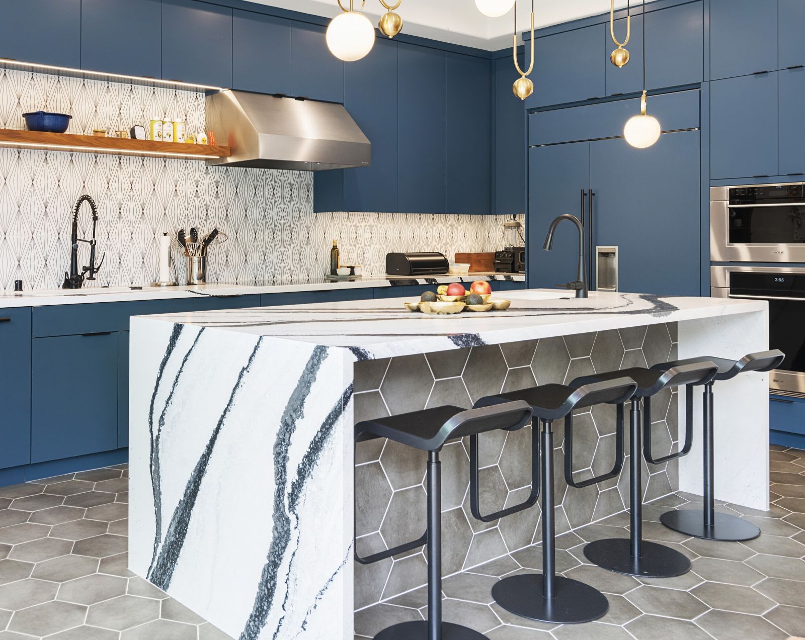 Navy blue kitchen by Murray Lampert with an induction cooktop, a waterfall island with dramatic veining, globe pendant lights, and hexagon floor tile