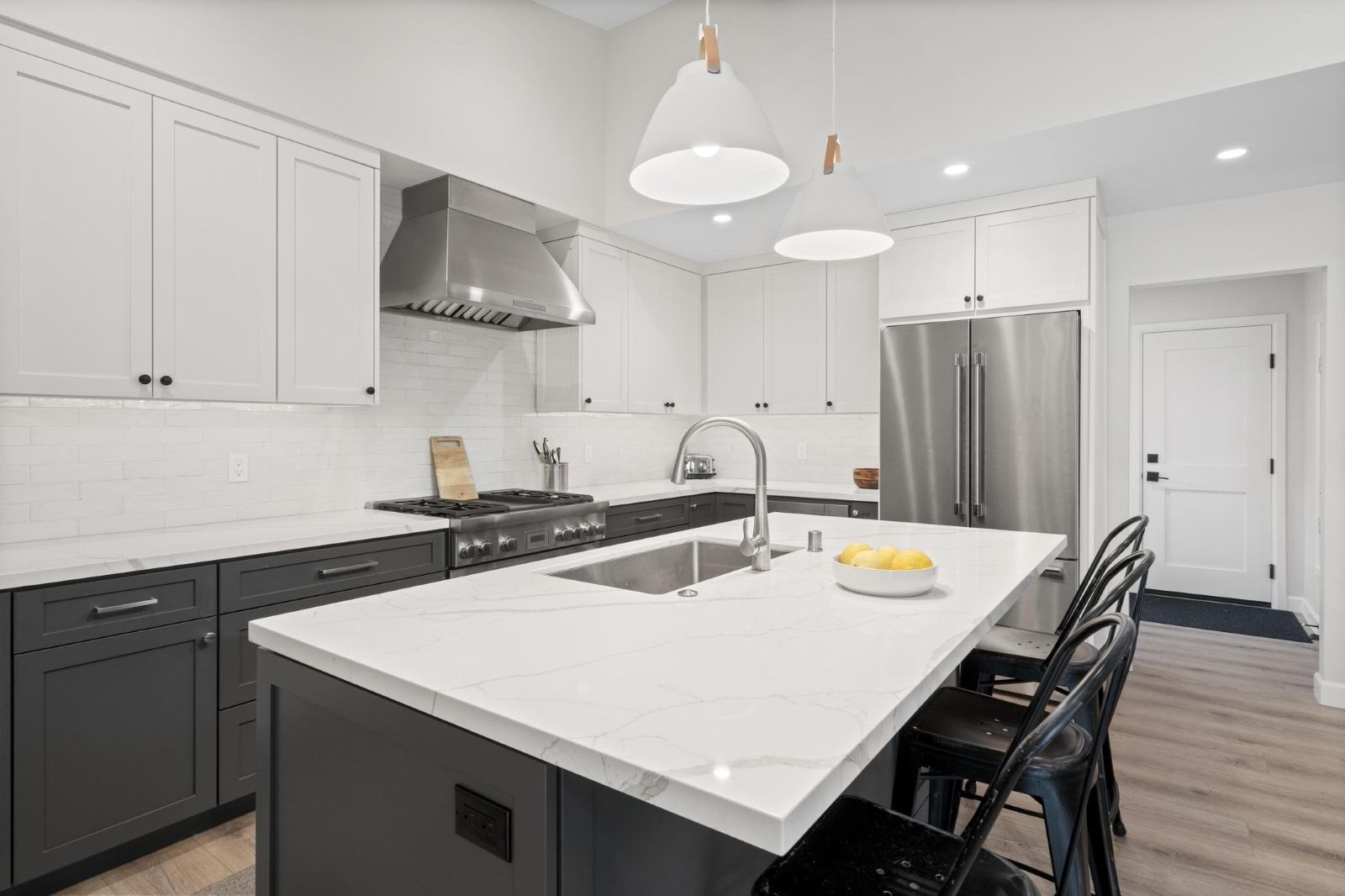 Two-tone kitchen remodel with white shaker upper cabinets, dark gray lowers, white quartz island, stainless appliances, and subway tile backsplash — San Diego by Murray Lampert Design, Build, Remodel