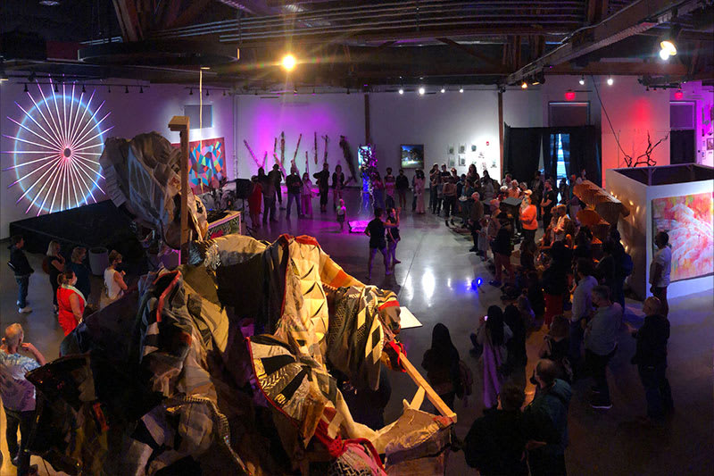 Crowd watching a performance by Capacitor at the Local Love Summer Art Festival in Oakland surrounded by art installations.