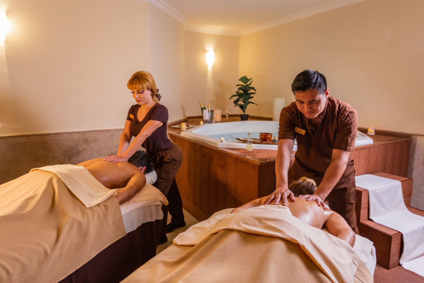 Two couples receiving simultaneous deep tissue massages in a dedicated spa treatment room at Sandos Cancun, featuring a large jetted tub. Perfect setup for executive incentives, VIP MICE attendees, and small group rewards.