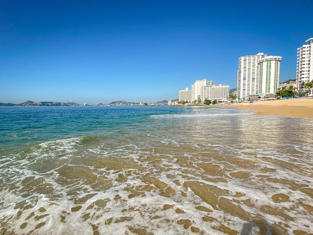 The shoreline of Acapulco with clear blue water and resort hotels along the beach