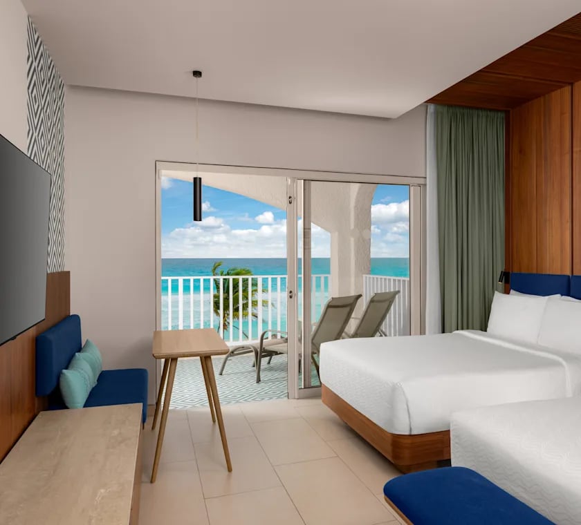 Modern oceanfront guest room at Hilton Cancun Mar Caribe All-Inclusive Resort, featuring two beds, a private balcony with Caribbean views, and ergonomic workspaces. Premium accommodations designed for corporate event attendees, executive retreats, and MICE incentive travel winners in Mexico.