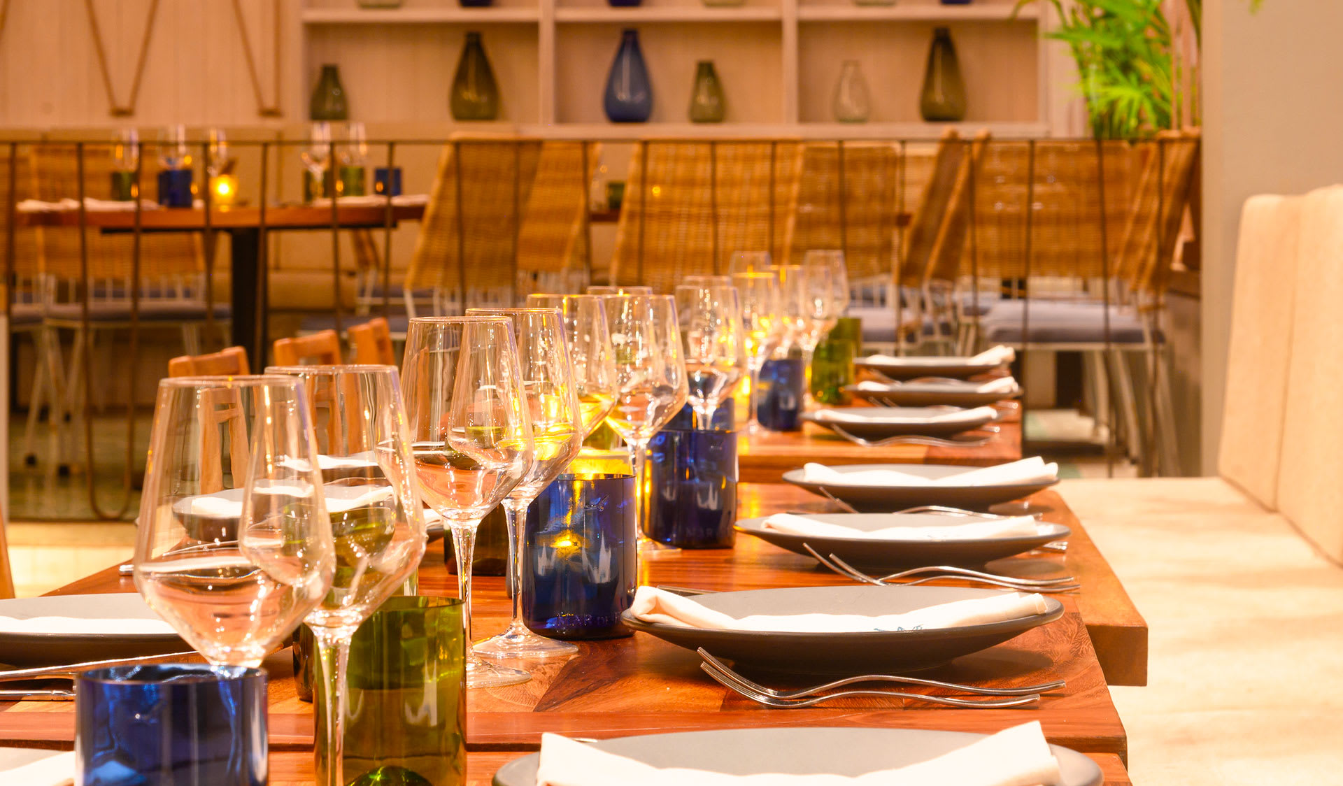 Close-up of an elegant dining table setup at Hotel Emporio Cancun, featuring polished glassware, wine glasses, and warm ambient lighting. A sophisticated venue for MICE industry gala dinners, corporate award ceremonies, and high-end banquet catering in Cancun, Mexico.