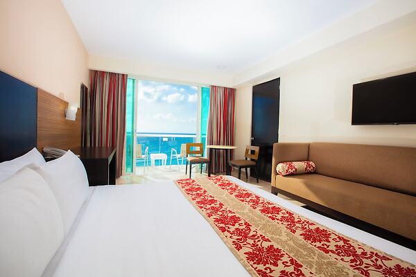 Ocean-view hotel room at Krystal Cancun featuring king bed, sofa, work table, and balcony—ideal for MICE travelers seeking comfort, connectivity, and scenic relaxation.